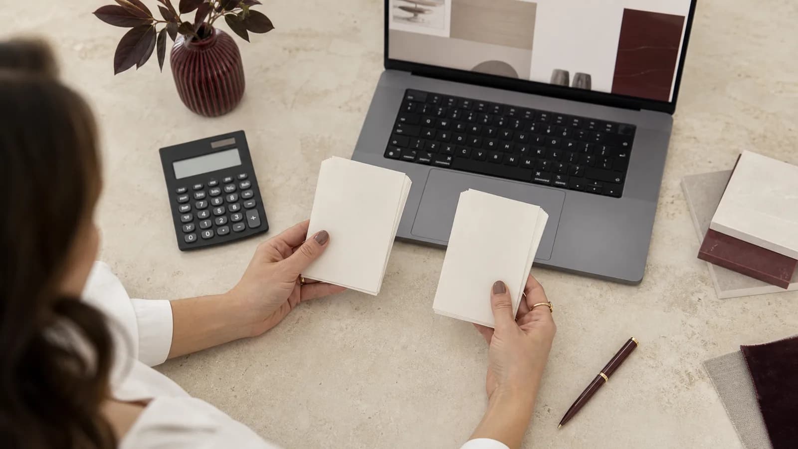 Studioinhaberin vergleicht zwei übersichtliche Kostenmodelle auf Papier neben einem Laptop.